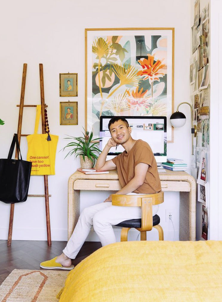 Person sitting at a desk in a home office with a large-scale, red and blue floral framed art print on the wall.