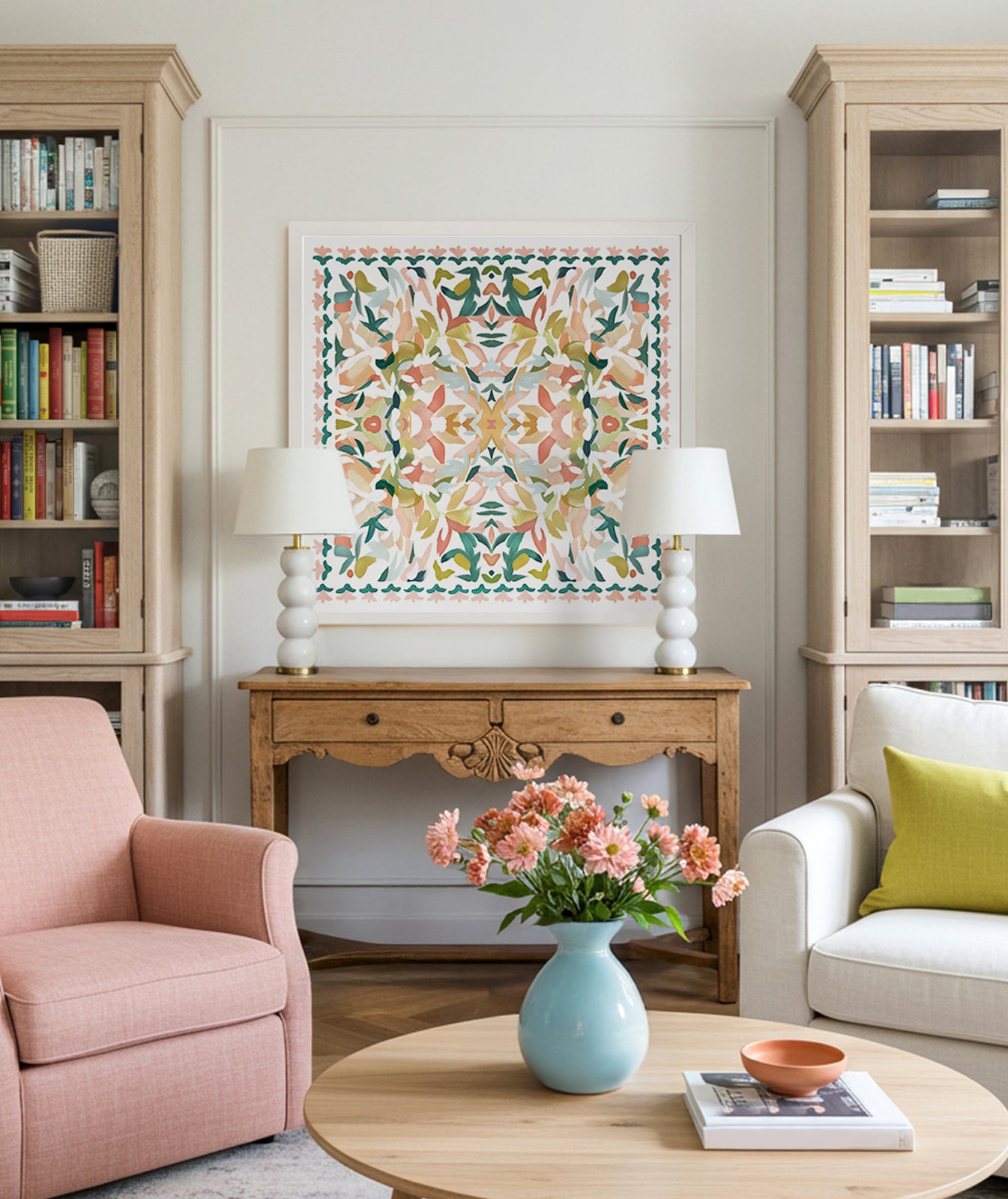 A living room with a large framed fine art print featuring a kaleidoscopic pattern in turquoise, green, pink, yellow and red colors with abstract floral elements, displayed above a wooden table.
