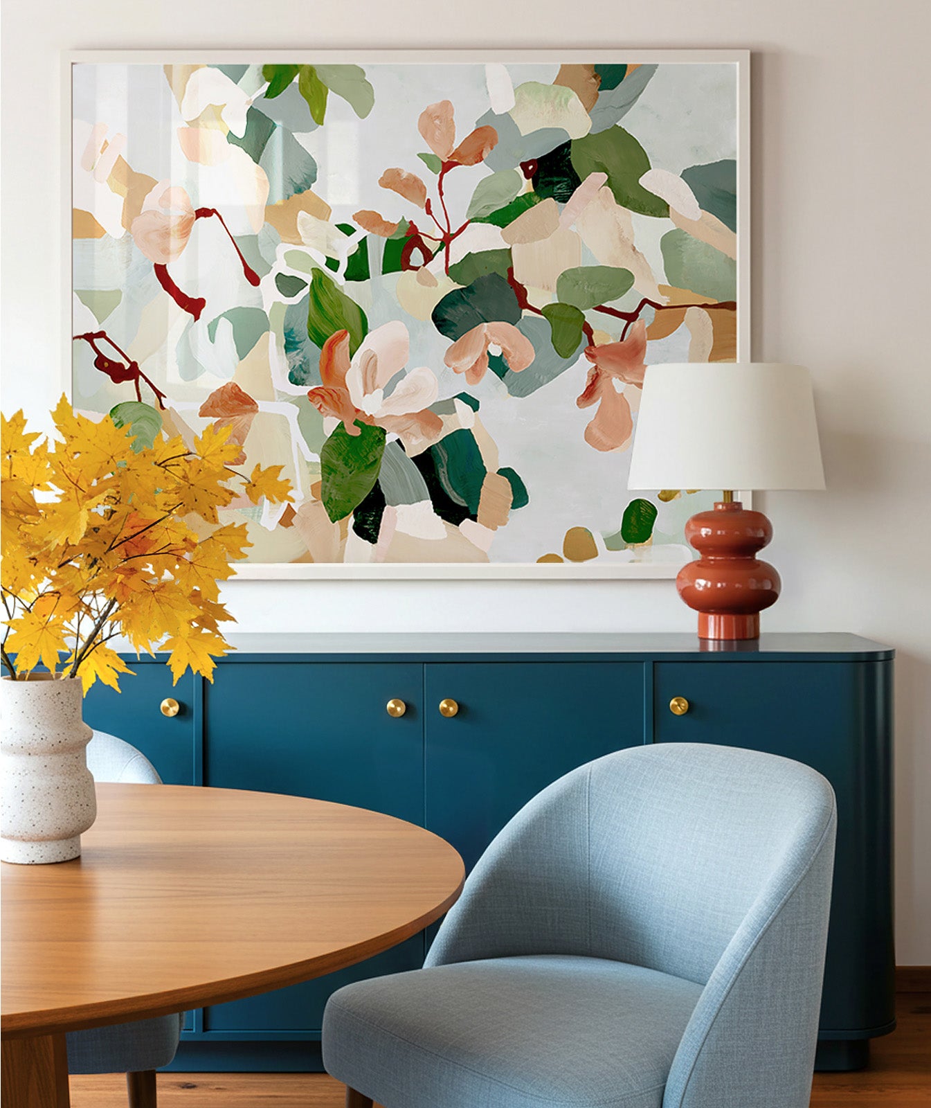Modern interior with a large framed abstract floral painting in blues, soft reds and greens above a dark blue cabinet, and light blue chair.
