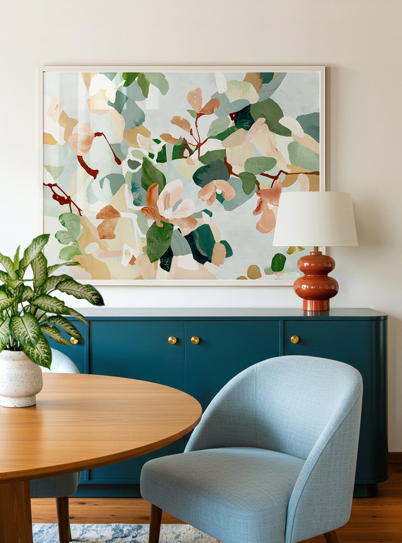 Large-scale abstract floral art featuring soft reds, light pinks, dark muted blues, greens and light blue-gray colors displayed above a blue cabinet in a dining room.