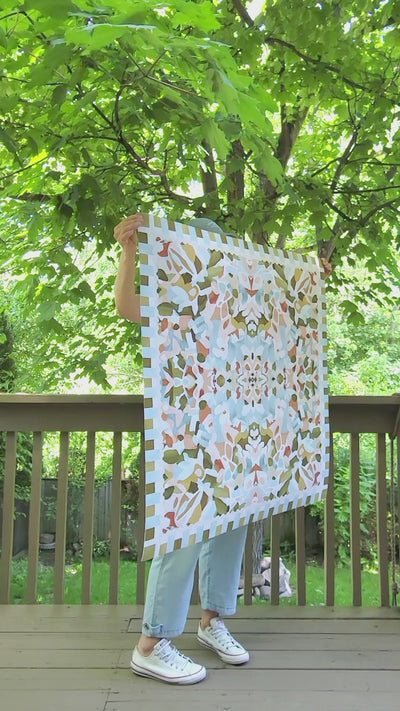 Video of the artist showcasing various large-scale art prints outdoors. The art prints are square with abstract floral patterns in colorful palettes.