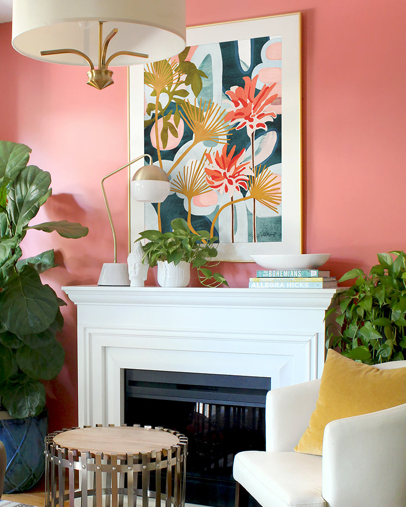 A framed, abstract floral art print featuring An abstract floral art print featuring red, green, yellow, light blue and dark blue colors displayed above a white fireplace in a living room.